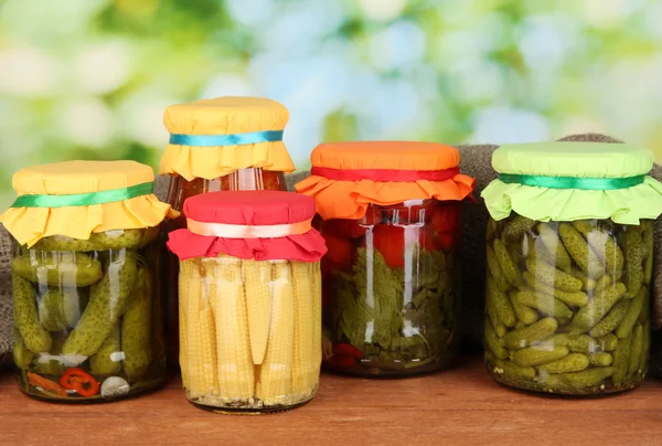 Jars with canned vegetables on green background close-up — Stock Photo, Image