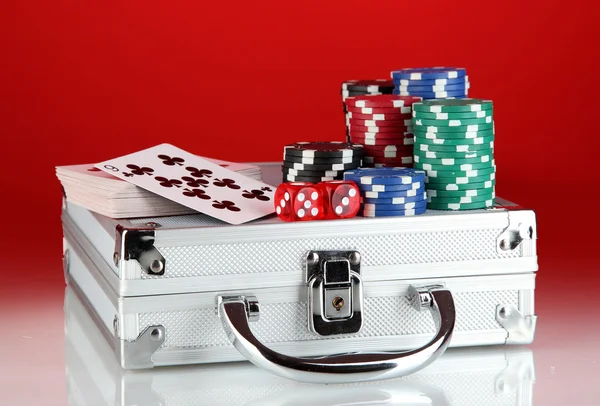 Jeu de poker sur un étui métallique sur fond rouge vif — Photo