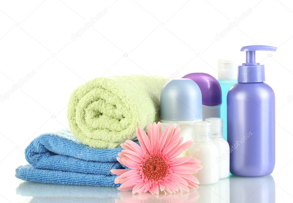 Cosmetics bottles with towels and flower isolated on white