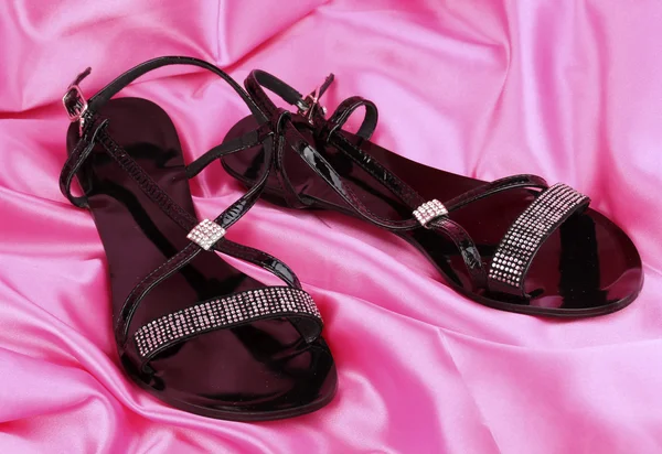 Schwarze Sandalen auf rosa Stoff — Stockfoto