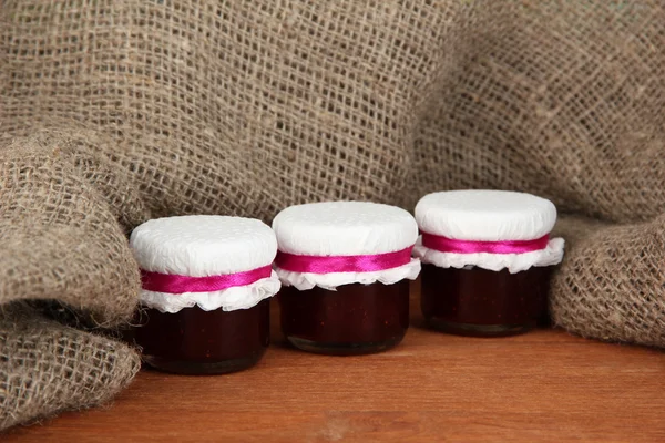 Little jars with strawberry jam on wooden background close-up — Stock Photo, Image