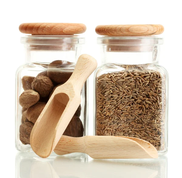 Jars and wooden spoons with nutmeg and cumin isolated on white — Stock Photo, Image