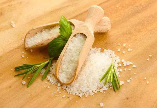 Salt in shovels with fresh basil, rosemary and thyme on wooden background — Stock Photo, Image