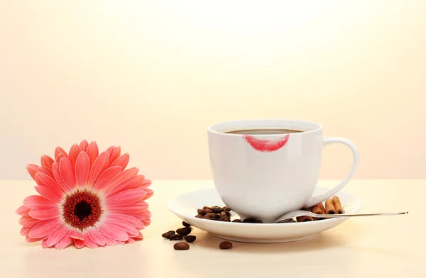 Tazza di caffè con segno di rossetto e fagioli gerbera, bastoncini di cannella sul tavolo di legno — Foto Stock