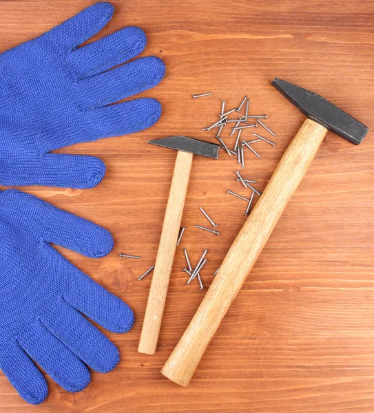 Kladiva a rukavice na dřevěné pozadí — Stock fotografie