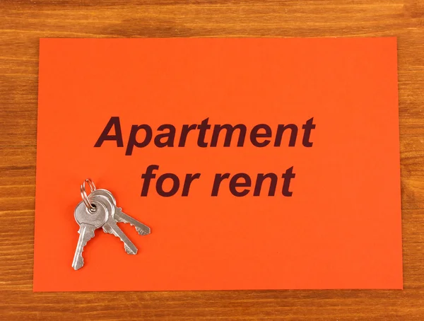 Anunciar apartamento de alquiler en papel rojo sobre fondo de madera primer plano — Foto de Stock