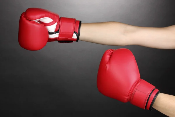 Красные боксерские перчатки на руках на сером фоне — стоковое фото