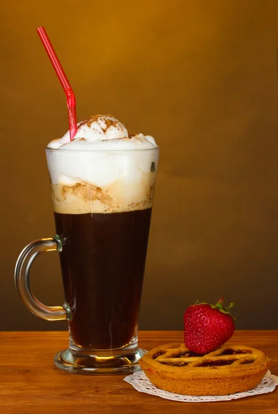 Vaso de café cóctel con tarta sobre tapete y fresa sobre fondo marrón —  Fotos de Stock