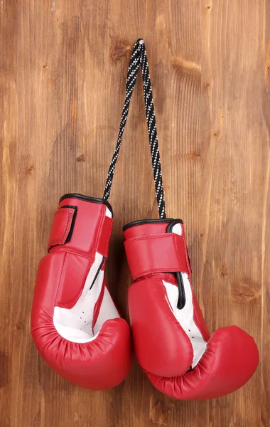 Röd boxningshandskar hängande på trä bakgrund — Stockfoto