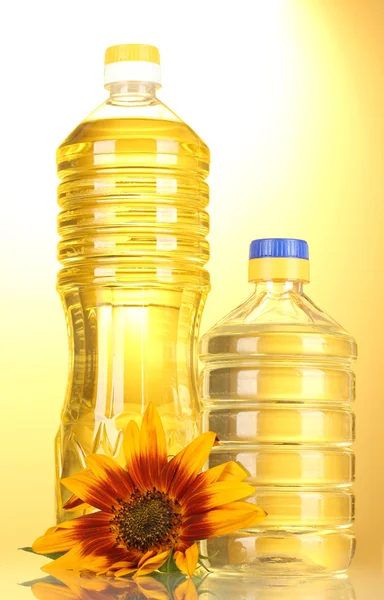 Sunflower oil and sunflowers on yellow background — Stock Photo, Image
