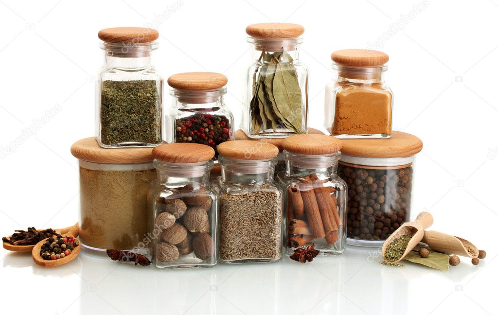 Jars and wooden spoons with spices isolated on white