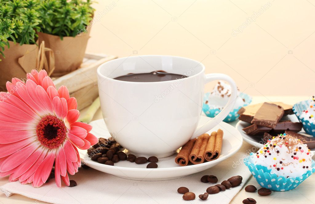 Cup of coffee and gerbera beans, cinnamon sticks on wooden table