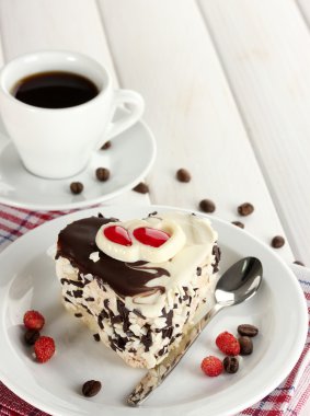 Sweet cake with chocolate on plate and cup of coffee on wooden table