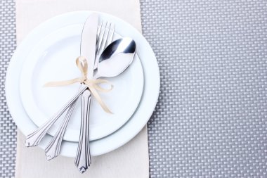 beyaz boş tabak çatal, kaşık ve bıçak ile bir şerit üzerinde gri bir masa örtüsü ile bağlıdır.
