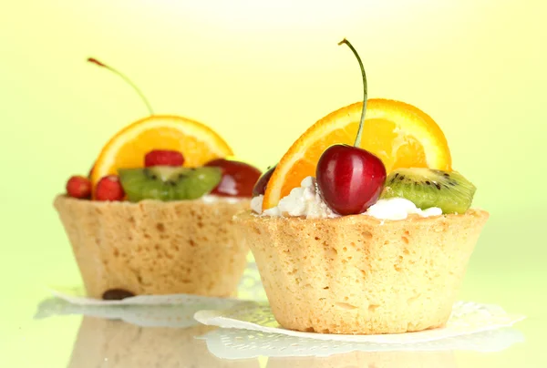 Süße Kuchen mit Früchten auf grünem Hintergrund — Stockfoto
