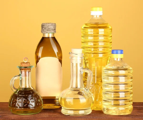 Aceite de oliva y girasol en las botellas y pequeños decantadores sobre fondo amarillo —  Fotos de Stock