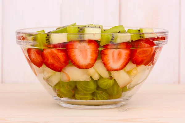 Gemengd fruit en bessen in glas op servet op houten achtergrond — Stockfoto