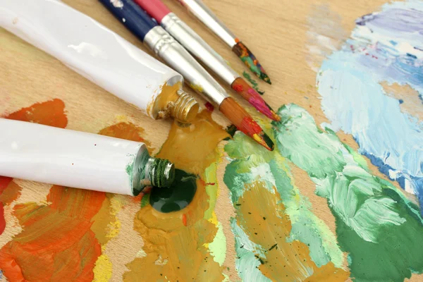 Soyut akrilik boya, boya tüpleri ve fırçalar ahşap palet üzerinde — Stok fotoğraf