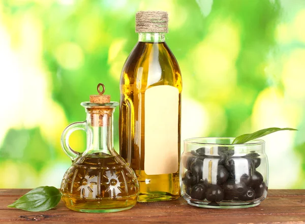 Olijfolie fles en kleine karaf op groene achtergrond — Stockfoto