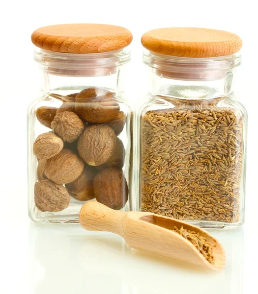Jars and wooden spoons with nutmeg and cumin isolated on white — Stock Photo, Image