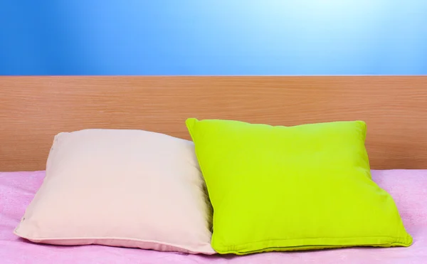 Jasne poduszki na łóżku na niebieskim tle — Zdjęcie stockowe