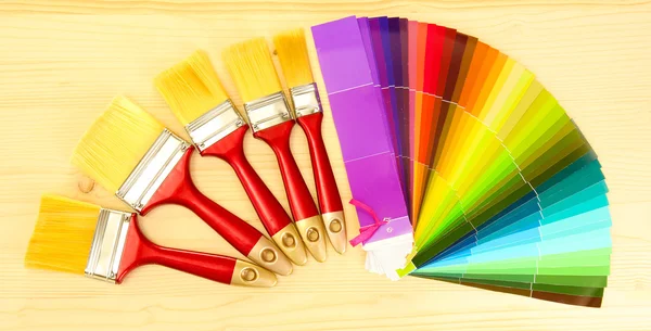 Pennelli e tavolozza luminosa di colori su sfondo di legno — Foto Stock