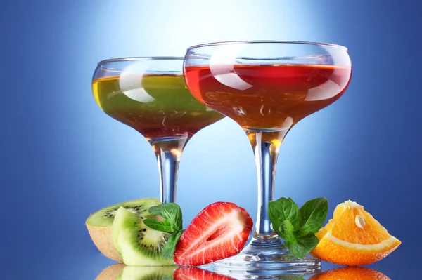 Geleia de frutas em copos e frutas no fundo azul — Fotografia de Stock
