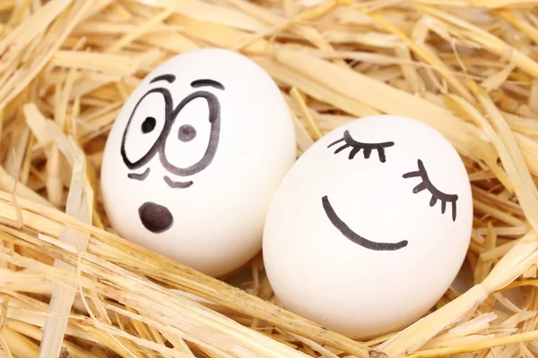 Huevos blancos con caras graciosas en paja — Foto de Stock
