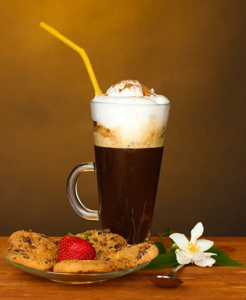 Bicchiere di caffè cocktail con biscotti e fragola su piattino e fiore su sfondo marrone — Foto Stock