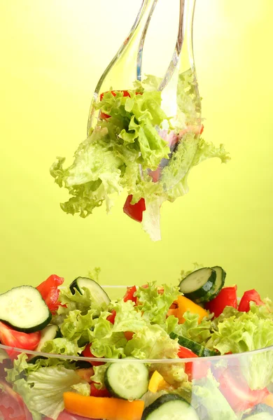 Salade de légumes frais dans un bol transparent avec cuillère et fourchette sur fond vert — Photo