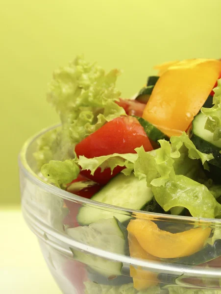 Färska grönsaker sallad i transparent skål på grön bakgrund — Stockfoto