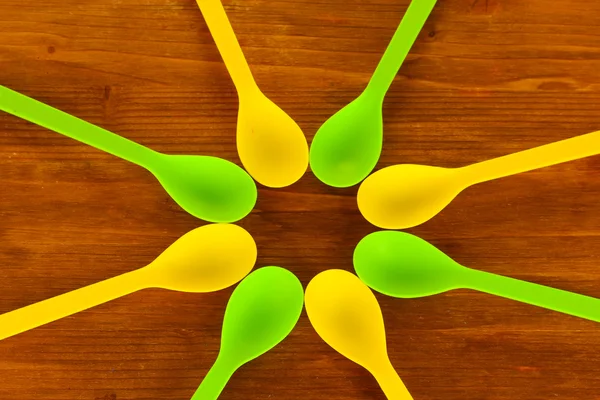 Bright plastic disposable spoons on wooden table close-up — Stock Photo, Image