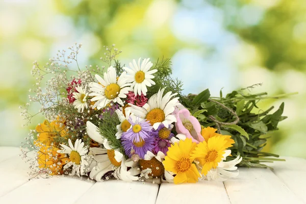 Hermoso ramo de flores silvestres brillantes, sobre mesa de madera sobre fondo verde —  Fotos de Stock
