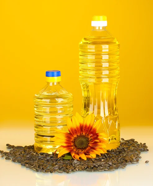 Óleo de girassol em garrafas de plástico no fundo amarelo — Fotografia de Stock