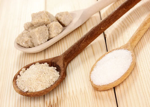 White and brown sugar in spoons on wooden background — Stock Photo, Image