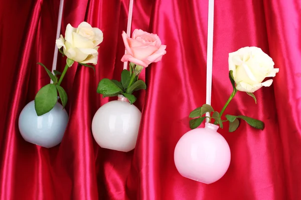 Hermosas rosas en jarrones colgando sobre fondo de tela —  Fotos de Stock