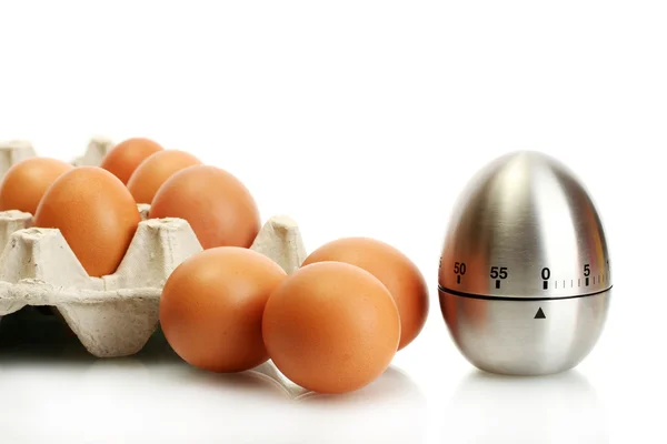 Яйца в коробке и яйцо таймер изолирован на белом — стоковое фото