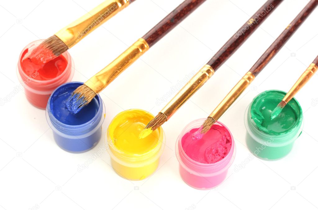 Brushes on the jars with colorful gouache on white background close-up