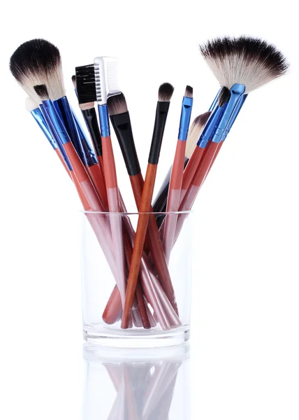 Escovas de maquiagem em copo de vidro isolado em branco — Fotografia de Stock