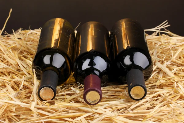 stock image Bottles of great wine on hay on brown background