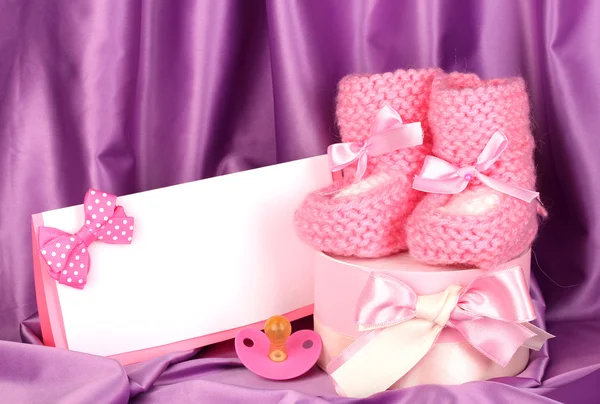 Botas de bebé de color rosa, pacifierd, postal y regalos sobre fondo de seda —  Fotos de Stock