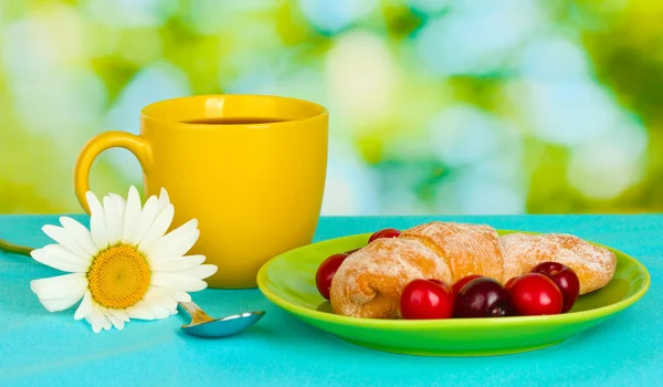 Croissant with cherries and coffee on wooden table on green background — Stock Photo, Image