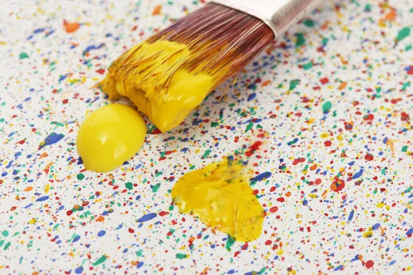 Pincéis com tinta colorida em salpicos coloridos fundo close-up — Fotografia de Stock
