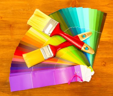 Paint brushes and bright palette of colors on wooden background clipart