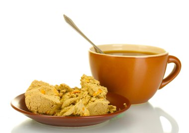 A cup of tea and saucer with delicious halva isolated on white clipart