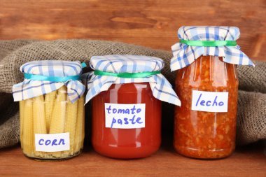 Jars with canned vegetables on wooden background close-up clipart