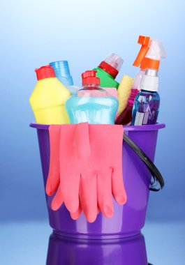 Bucket with cleaning items on blue background clipart