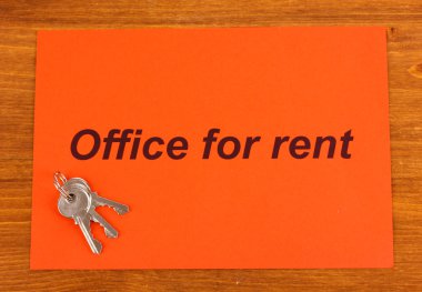 Advertise rental office on red paper on wooden background clipart