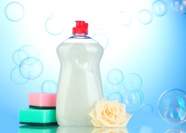 Dishwashing liquid with sponges and flower on blue background clipart