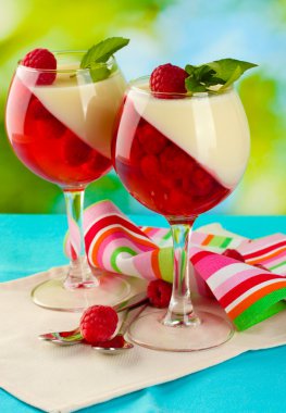 Fruit jelly in glasses, berries and mint on table on green background clipart